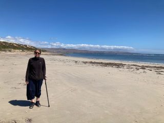 CC walks on the beach with a walking stick after her operation
